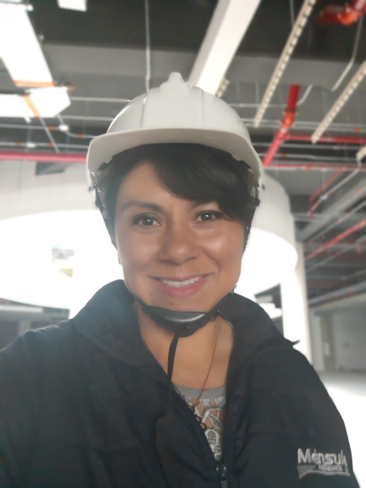 Lina Rodríguez avec casque sur le chantier, sous les réseaux techniques